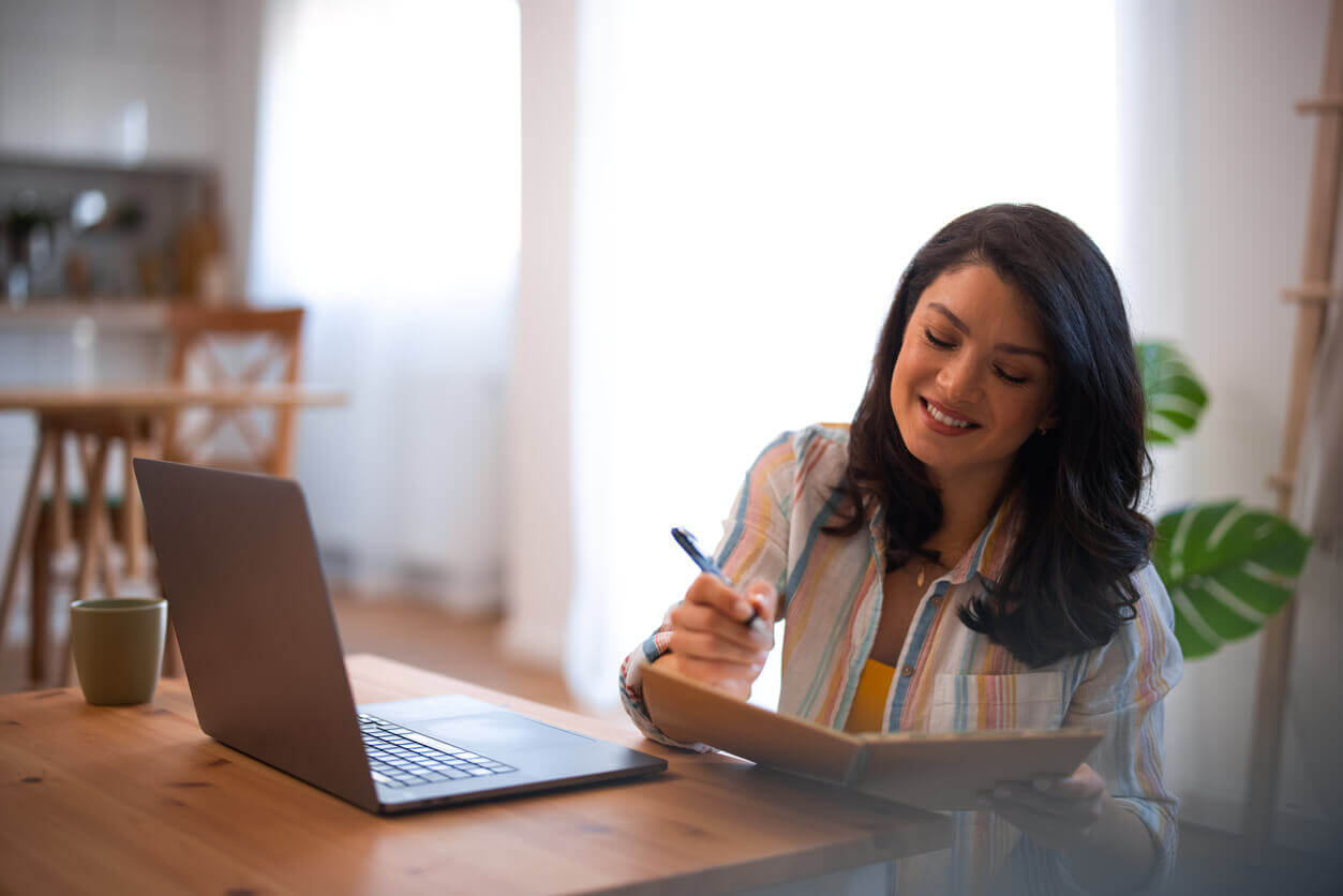 A smiling woman working at a table with a laptop, representing the benefits of segregated funds.