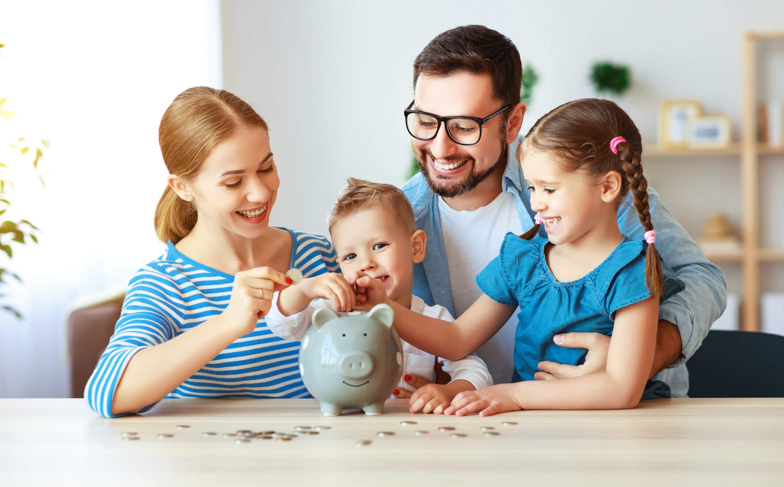 Happy family saving money in a piggy bank, representing financial planning services - Cardinal Life.