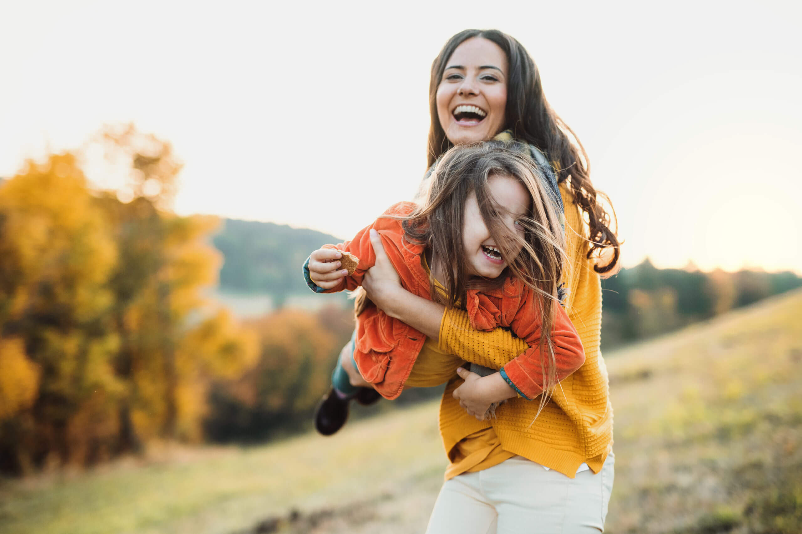 Happy mother playing with her daughter in a park, representing living benefits services - Cardinal Life.